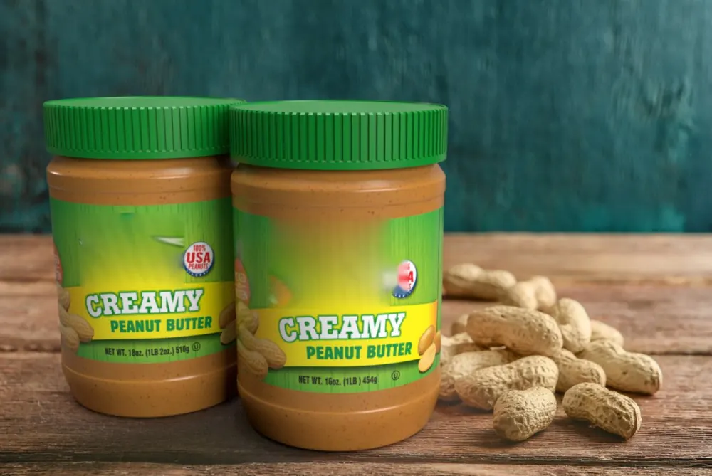 Jars of creamy peanut butter with peanuts